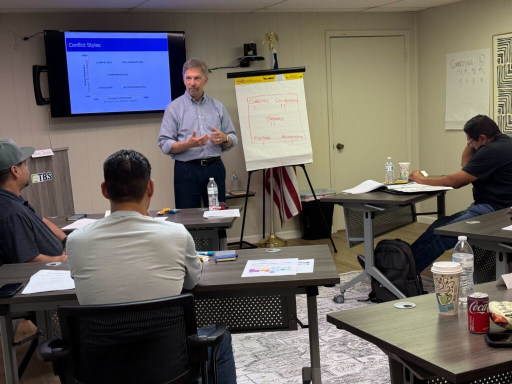 Instructor leading a leadership development session for new supervisors, speaking to participants seated at desks during a professional training workshop.